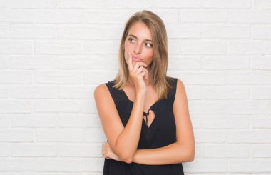 Beyaz tuğla duvar ciddi bir yüz düşünme hakkında soru, çok karışık fikir güzel genç kadın