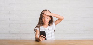 Genç İspanyol çocuğun kafasına, el ile vurguladı smartphone kullanarak masada oturan şok utanç ve sürpriz suratla, öfkeli ve sinirli. Korku ve hata için üzgün.