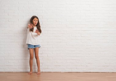 Genç İspanyol çocuğun stading beyaz tuğla duvarın korkuyor ve dehşete şokta bağırarak el ile korku ifade dur hareketi ile üzerinden. Panik kavramı.