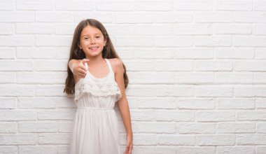 Genç İspanyol çocuk dostu sunan el sıkışma tebrik ve davet edici olarak gülümseyen beyaz tuğla duvarın üzerinden. Başarılı iş.