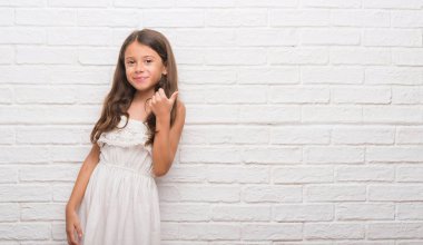 Genç İspanyol çocuğun hareketi el ile mutlu yaşasın yapıyor beyaz tuğla duvarın üzerinden. Kameraya bakarak başarı gösteren ile ifade onaylama.