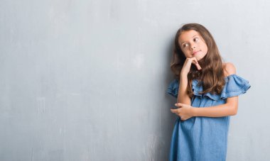 Grunge gri duvar çene düşünme hakkında soru, dalgın ifade üzerine el ile genç İspanyol çocuk. Düşünceli yüzüyle gülümsüyor. Şüphe kavramı.