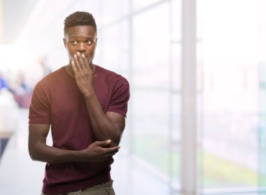 Genç Afro-Amerikan adam kapak ağız el için hata, ifade korku, utanç ile şok ile sessizlik içinde gizli kavramı korkuttu