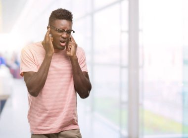 Pembe tişört kapsayan kulakları parmakları ile yüksek sesle müzik gürültü rahatsız ifade ile giyen genç Afro-Amerikan adam. Sağır kavramı.