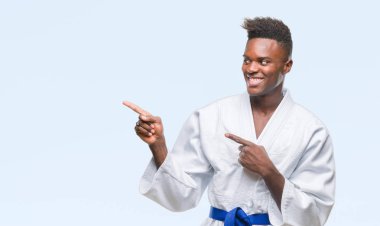İzole arka plan gülümseyen ve iki elleri ve parmakları ile tarafına işaret kamera bakarak kimono giyen genç Afro-Amerikan adam.
