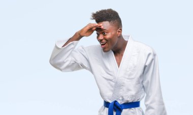 İzole arka plan çok mutlu ve gülümseyen uzakta el ile üzerine kafa seyir kimono giyen genç Afro-Amerikan adam. Arama kavramı.