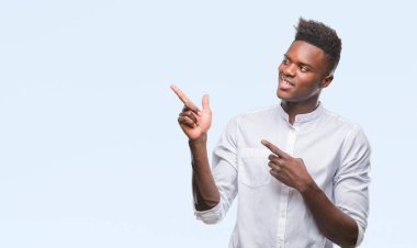 Gülümseyen ve iki elleri ve parmakları ile tarafına işaret kamera bakarak izole arka plan üzerinde genç Afro-Amerikan adam.