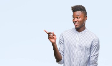 Kameraya bakarak yan el ve parmak ile işaret eden genç Afro-Amerikan adam yüzünde kocaman bir gülümseme ile izole arka plan üzerinde.