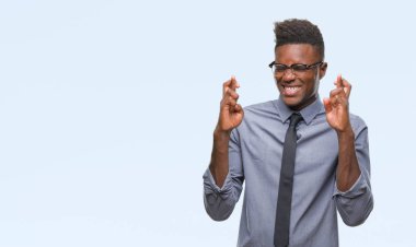 Umut ve gözleri kapalı geçiş parmaklarıyla gülümseyen izole arka plan üzerinde genç Afro-Amerikalı iş adamı. Şans ve batıl kavramı.