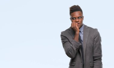 Stresli ve gergin elle çivi ısırma ağzına bakarak izole arka plan üzerinde genç Afro-Amerikalı iş adamı. Anksiyete sorunu.