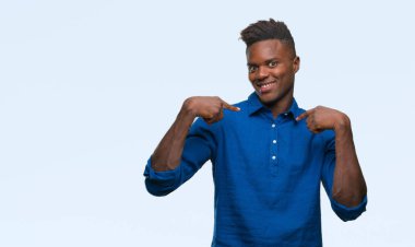 Yüzünde gülümseme ile kendinden emin görünüyorsun, kendini gururlu ve mutlu parmakları ile işaret izole arka plan üzerinde genç Afro-Amerikan adam.