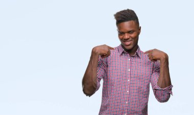 Yüzünde gülümseme ile kendinden emin görünüyorsun, kendini gururlu ve mutlu parmakları ile işaret izole arka plan üzerinde genç Afro-Amerikan adam.