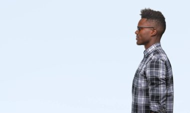 Genç Afro-Amerikan adam giyen güneş gözlüğü izole arka tarafına, seyir üzerinde dinlenmek doğal yüz emin gülümseme ile pozuyla profili.