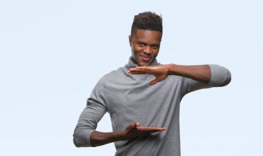 Afrikalı-Amerikalı genç izole arka plan ile büyük ve büyük boy işaret, ölçü birimi sembol gösteren el eller üzerinde. Kameraya bakarak gülümsüyordu. Ölçüm kavramı.