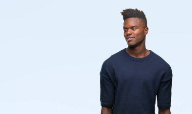 Afrikalı-Amerikalı genç uzak tarafına yüzünde, doğal ifade gülümseme ile seyir izole arka plan üzerinde. Kendine güvenen gülüyor.