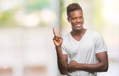 Afrikalı-Amerikalı genç mutlu yüz zafer işareti yaparken kameraya göz kırpıyor ile gülümseyen izole arka plan üzerinde. İki numaralı.