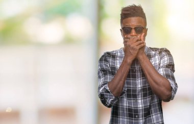 Üzerinde güneş gözlüğü takmış genç Afro-Amerikan adam arka plan ağız hata için elleriyle kapsayan şok izole. Gizli kavramı.