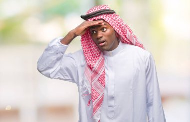 Geleneksel keffiyeh üzerinde giyen genç Arapça Afrika adam arka plan çok mutlu ve gülümseyen uzakta el ile üzerine kafa seyir izole. Arama kavramı.