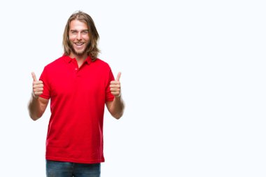 El ile pozitif jest yapıyor izole arka plan başarı işareti üzerinde uzun saçlı yakışıklı delikanlı başparmak gülümseyen ve mutlu. Neşeli bir ifadeyle, kazanan jest kameraya bakıyor.