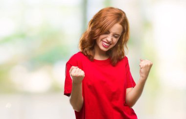 Gülümseyen ve başarı için çığlık genç güzel kadın izole arka plan çok mutlu ve heyecanlı kaldırdı, silah ile kazanan jest yapıyor. Kutlama kavramı.