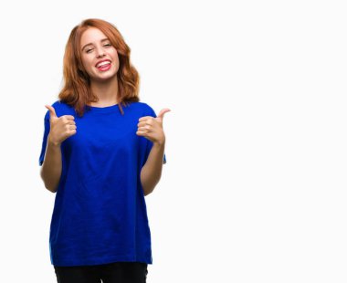 Genç güzel kadın el ile pozitif jest yapıyor izole arka plan başarı işareti yüzünden başparmak gülümseyen ve mutlu. Neşeli bir ifadeyle, kazanan jest kameraya bakıyor.