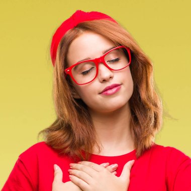 Genç güzel kadın ile gülümseyen izole arka plan yüzünden kapalı gözler ve yüzünde minnettar jest ile göğüs üzerinde eller. Sağlık kavramı.