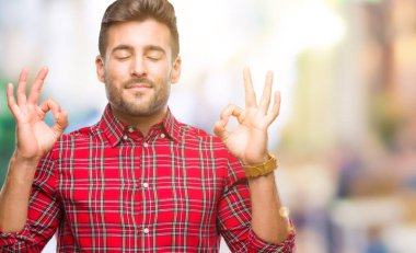 Yakışıklı delikanlı izole arka plan üzerinde dinlenmek ve gülümseyen gözlerle parmak ile meditasyon jest yapıyor kapalı. Yoga kavramı.