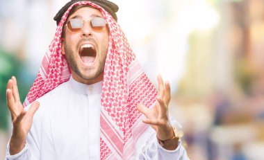 Keffiyeh üzerinde giyen genç yakışıklı adam arka plan deli izole ve deli bağırarak ve agresif ifade ve silah kaldırdı bağırıyor. Hayal kırıklığı kavramı.