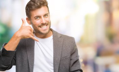 Genç yakışıklı iş adamı yapıyor gülümseyen izole arka plan üzerinde telefon hareketi ile el ve parmak telefonda konuşuyor gibi. Kavramları iletişim.