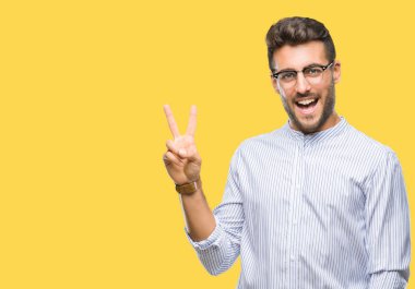 Mutlu yüz zafer işareti yaparken kameraya göz kırpıyor ile gülümseyen izole arka plan üzerinde genç yakışıklı adam. İki numaralı.