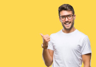 Seyir ve başparmak yanında yukarıyı mutlu yüz ile gülümseyen izole arka plan üzerinde gözlük takan genç yakışıklı adam.