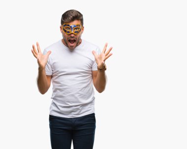 Üzerinde karnaval maskesi giyen genç yakışıklı adam deli kutluyor arka plan izole ve silah ile başarı için yükseltilmiş ve açık gözleri heyecanlı çığlık hayrete düşürdü. Kazanan kavramı