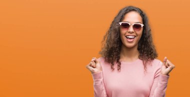 Güzel genç İspanyol kadın kutluyor güneş gözlüğü takıyor şaşırttı ve silah ile başarı için yükseltilmiş ve açık gözler hayrete düşürdü. Kazanan kavramı.