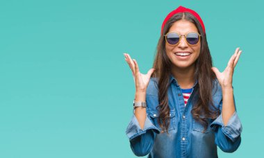 Genç güzel Arap kadın deli ve çığlık kaldırdı ve kapalı gözleri heyecanlı silah ile başarı için deli kutluyor izole arka plan üzerinde güneş gözlüğü takıyor. Kazanan kavramı