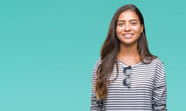 Genç güzel Arap kadın yüzünde mutlu ve güzel bir gülümseme ile izole arka plan üzerinde güneş gözlüğü takıyor. Şanslı kişi.