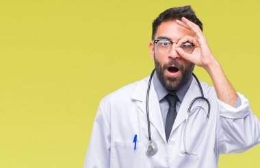 Sürpriz yüz, göz parmaklarının arasından seyir yetişkin İspanyol doktor adam ok jest yapıyor izole arka plan üzerinde şok. İmansız ifade.