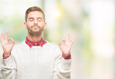 Genç yakışıklı adam giyen kış kazak izole arka plan üzerinde dinlenmek ve gülümseyen gözlerle parmak ile meditasyon jest yapıyor kapalı. Yoga kavramı.