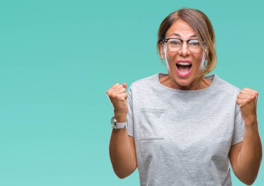 İzole arka plan üzerinde kutluyor gözlük takan orta yaş İspanyol kadın kıdemli şaşırttı ve silah ile başarı için yükseltilmiş ve açık gözler hayrete düşürdü. Kazanan kavramı.