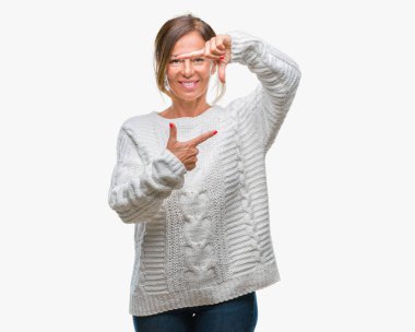 Elle yapma çerçeve ve parmakları ile mutlu yüz gülümseyen izole arka plan üzerinde kış kazak giyen orta yaş üst düzey İspanyol kadın. Yaratıcılık ve Fotoğrafçılık kavramı.