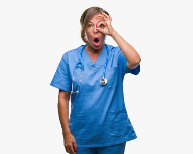 Orta yaş kıdemli hemşire doktor kadın izole arka plan ok jest sürpriz yüz, göz parmaklarının arasından seyir şok yapıyor. İmansız ifade.