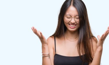 Kızgın ve çığlık kaldırdı ve kapalı gözleri heyecanlı silah ile başarı için deli kutluyor izole arka plan üzerinde gözlük takan Genç Asyalı kadın. Kazanan kavramı