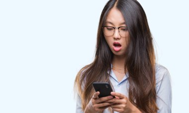 Genç Asyalı kadın manifatura Smartphone izole arka şok sürpriz yüzü, korkuyor ve korku ifadesi ile heyecanlı olan korkmuş üzerinde kullanma