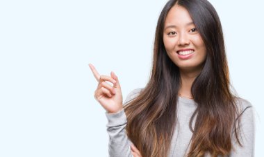 Kameraya bakarak yan el ve parmak ile işaret eden Genç Asyalı kadın yüzünde kocaman bir gülümseme ile izole arka plan üzerinde.