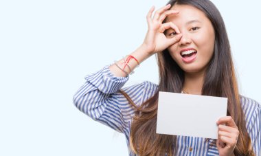 Mutlu yüz el parmaklarının arasından seyir göz üzerinde ok işaretiyle yapıyor gülümseyen izole arka plan üzerinde boş kartı tutan Genç Asyalı kadın