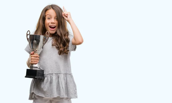 Brunette Hispanic Girl Holding Trophy Surprised Idea Question Pointing Finger — Stock Photo, Image