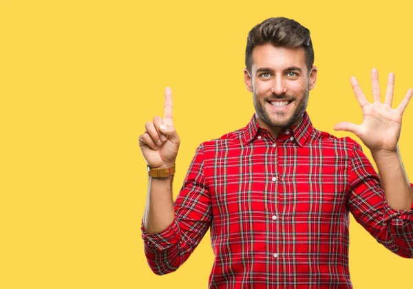 Yakışıklı delikanlı gösterilen ve parmakları ile işaret izole arka plan üzerinde kendinden emin ve mutlu gülümseyerek süre 6 numara.