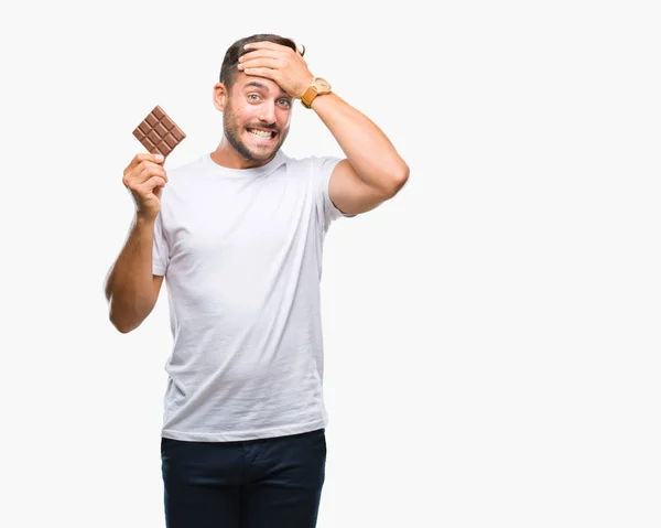 Homem Bonito Jovem Comendo Barra Chocolate Sobre Fundo Isolado Estressado — Fotografia de Stock