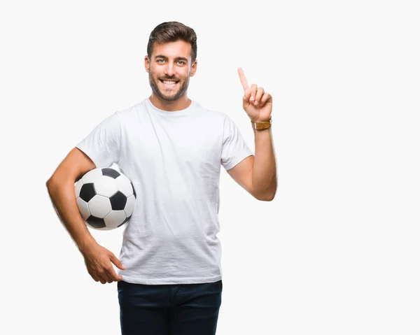 幸せそうな顔 ナンバーワンのアイデアや質問ポインティング指でびっくりの孤立した背景にサッカー サッカー ボールを保持している若いハンサムな男 — ストック写真