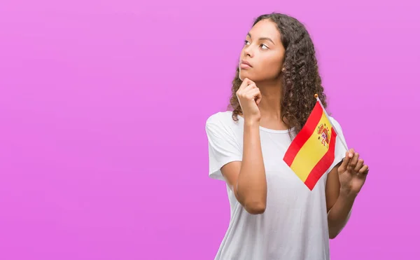 Молодий Латиноамериканського Жінка Тримає Прапор Іспанії Серйозним Обличчям Думаючи Про — стокове фото