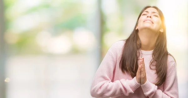 年轻漂亮的拉美裔女子穿着一件毛衣乞讨 双手合十祈祷 脸上表情非常激动和担忧 请求宽恕 宗教概念 — 图库照片
